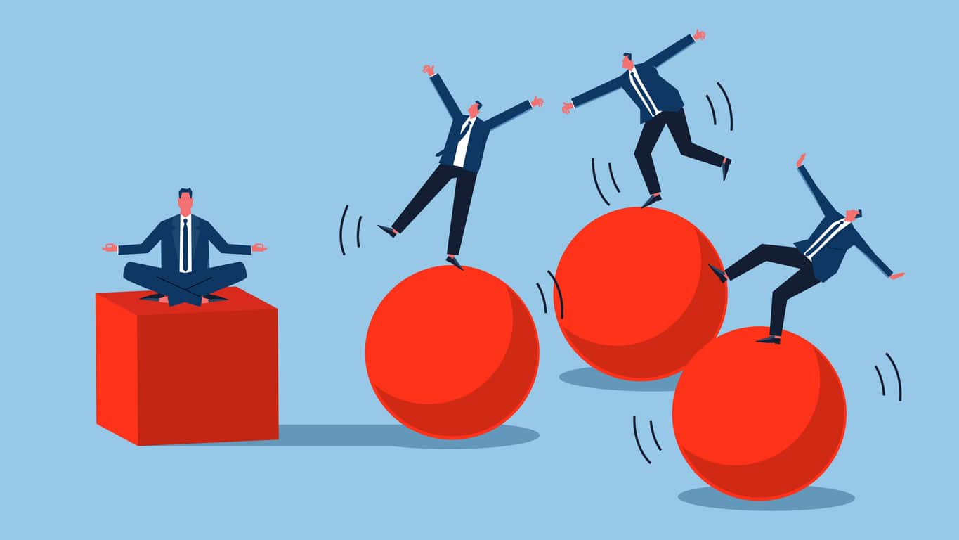 Volatility versus stability, risk and uncertainty, one group of businessmen sitting cross-legged on a stable cube, another group of businessmen on a sphere unable to maintain balance